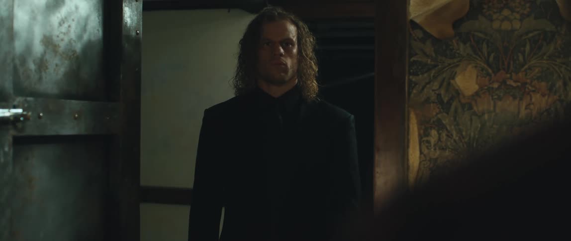 Man stands in a doorway then closes the door as another man runs towards the closed door and puts his hands on it