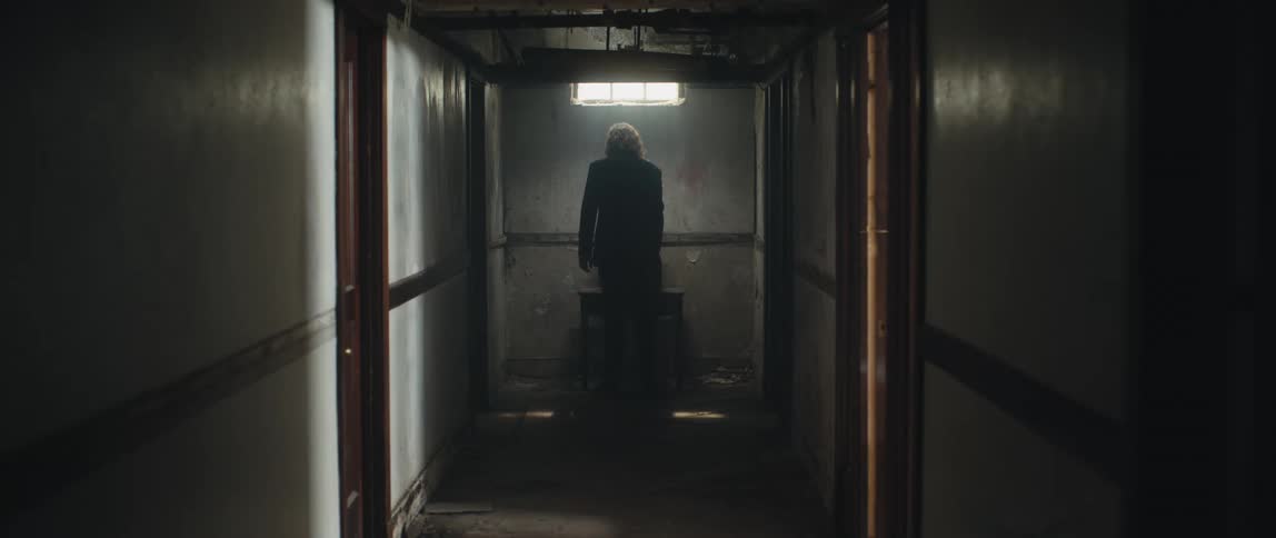 A man is walking down the hallway of a run down building