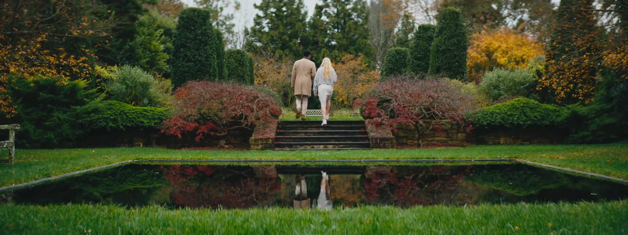 Attractive couple walk and talk in a magic garden with a reflecting pool