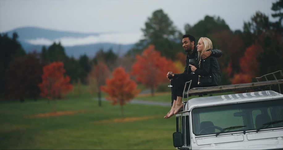 Mixed race couple enjoys wine with beautiful fall color in the mountains