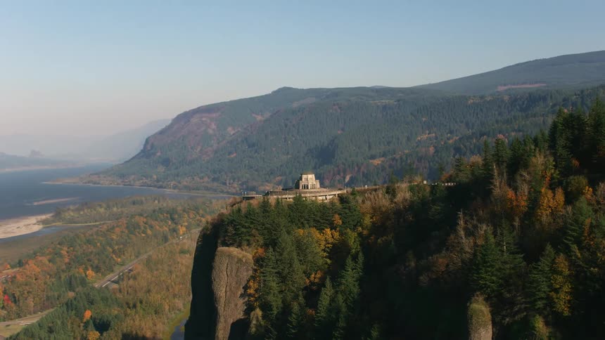 A castle sits on a cliff over a river and highway