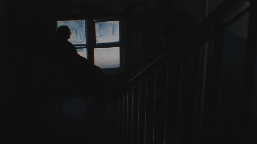 A man sits next to a window and looks at the snow covered ground
