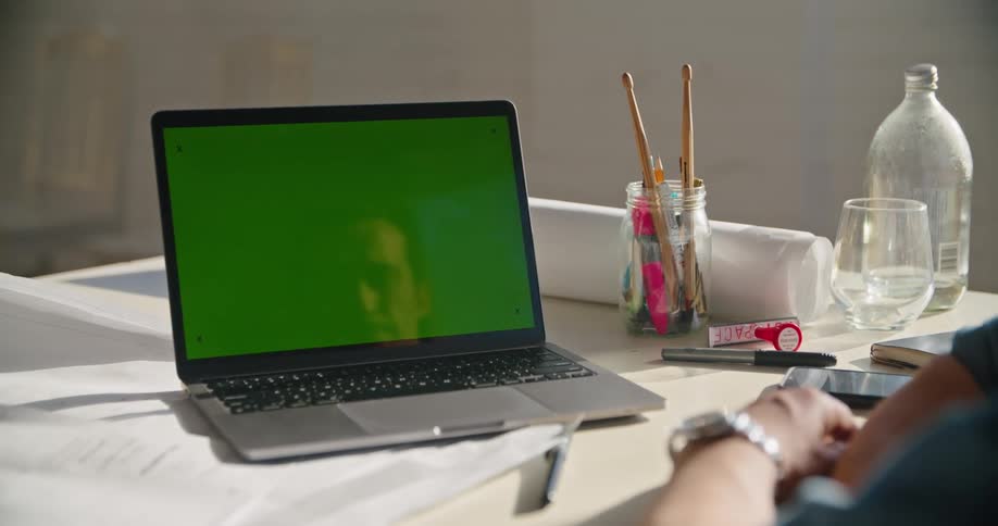 Man sits at table with papers rolled plans and a laptop