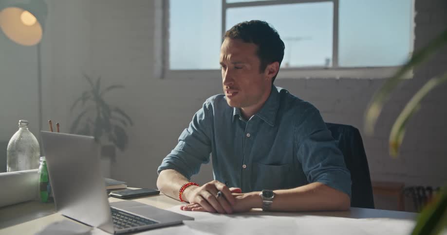 A man is having a video chat in his office during the daytime