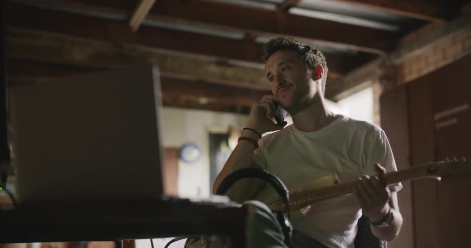A man playing guitar answers his phone