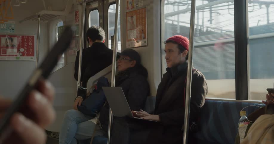 Man uses a laptop and looks around on a train