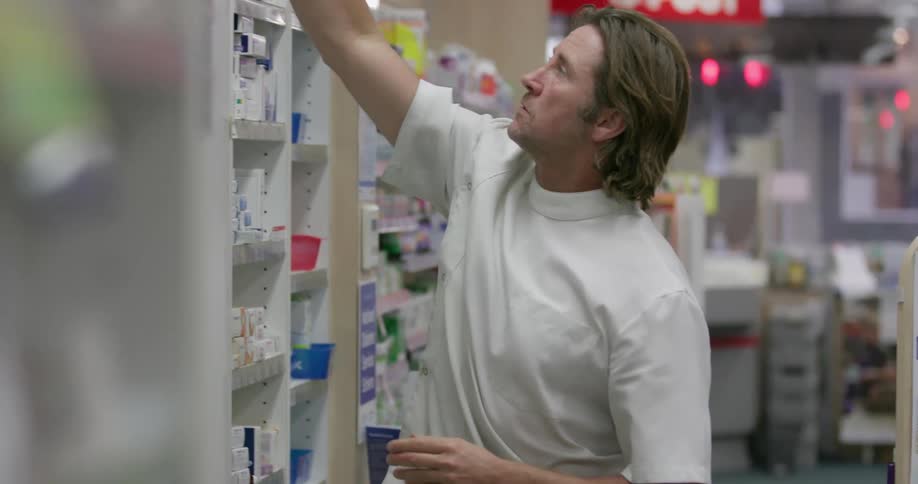 A pharmacist grabs a bottle of medication from a shelf