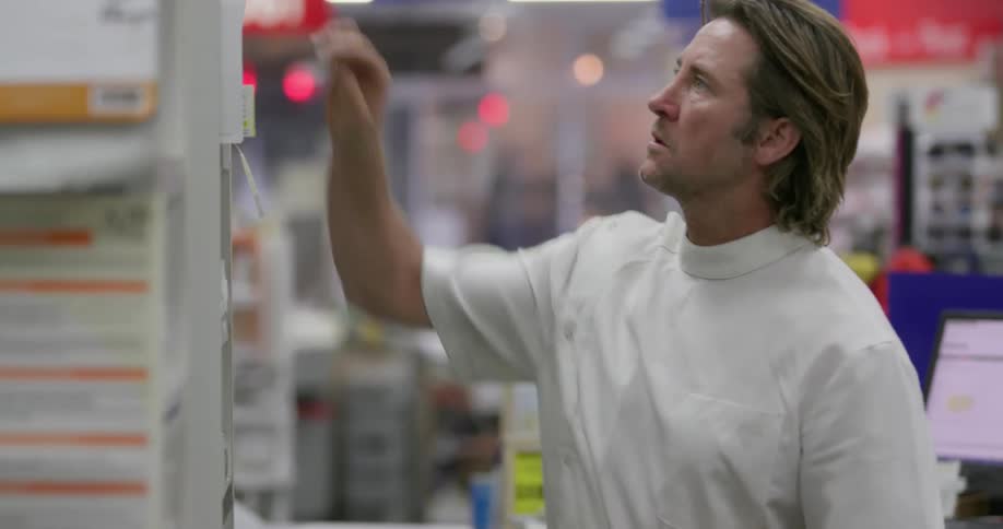 A pharmacist looks for medicine in a pharmacy