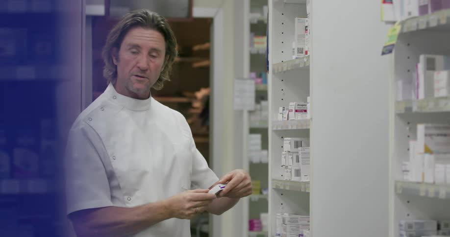 A pharmacist examines boxes in his shop