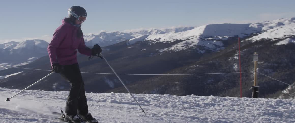 A person is skiing down a steep slope on a sunny day