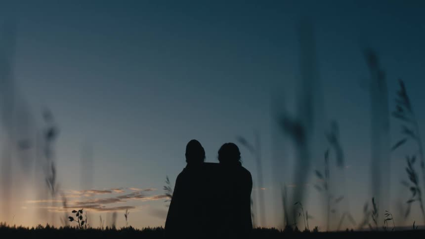 Two people sit watching the sunset