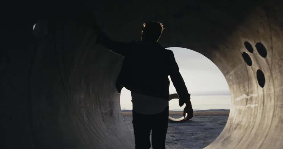A man walks through concrete tubes on the beach