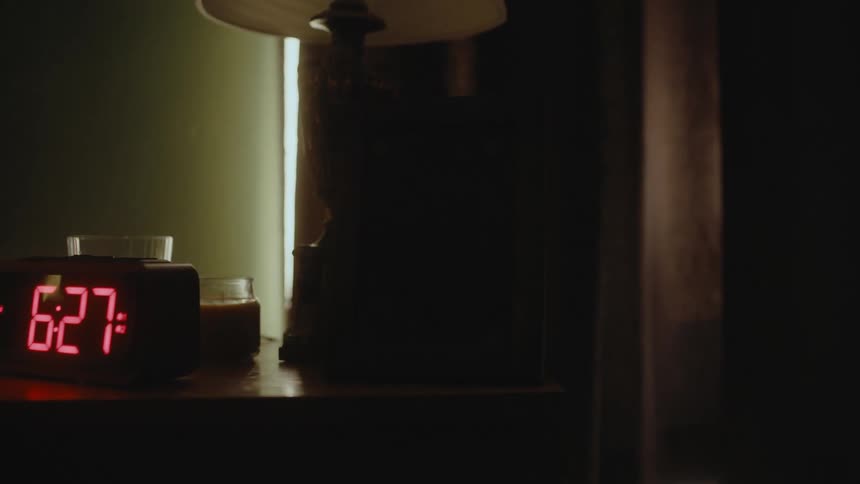 A digital clock radio on a nightstand changes to 628 am as daylight comes through the window