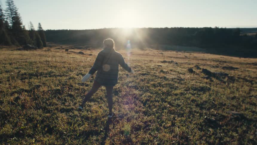 Two women are walking in a field as the sun shines brightly upon them