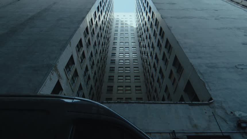 A van parked on the street in front of tall city apartment buildings