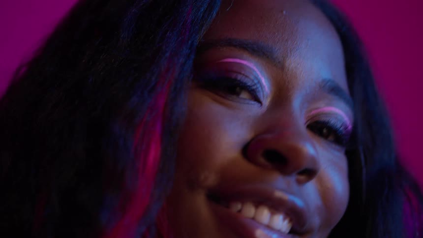 A teenage girl with bright pink eye makeup smiles