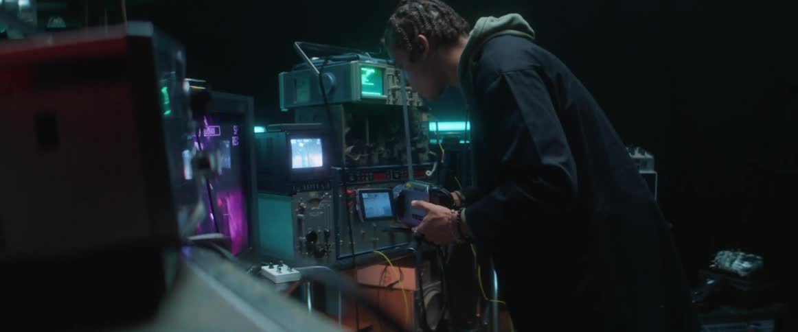 Man works with camcorder and views screens set among scientific devices