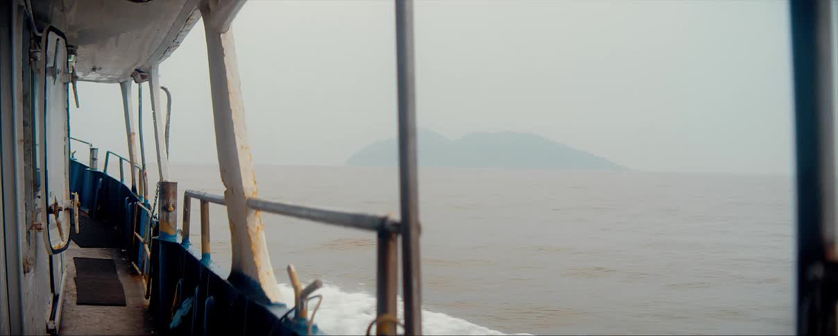 A boat sailing in the ocean with hills in the far off distance
