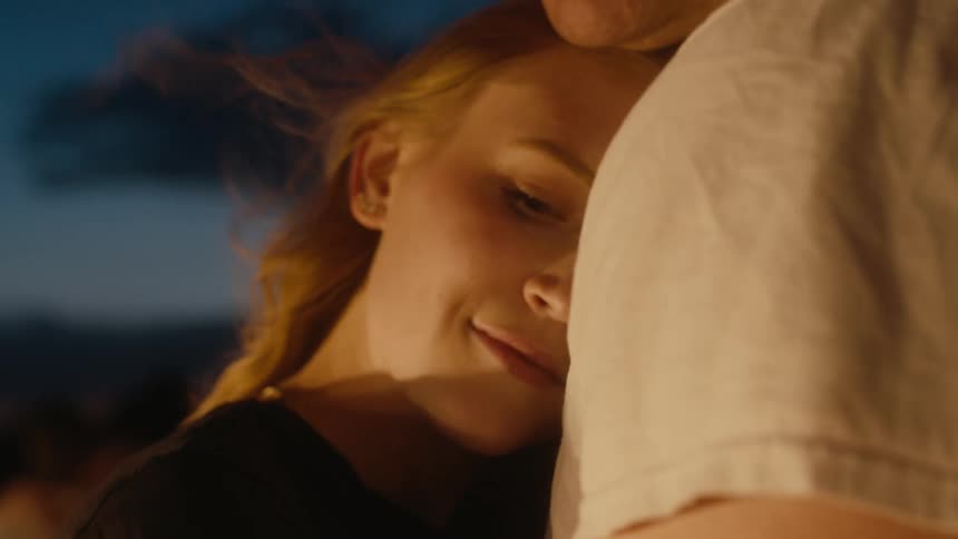 Woman smiles while hugging man outdoors on a windy day at night