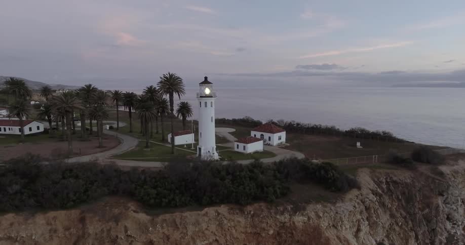 A lighthouse is shining on a cliff near the water