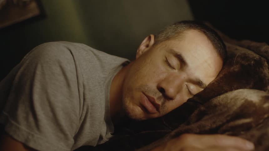 A man is sleeping on a couch and he opens his eyes and looks around