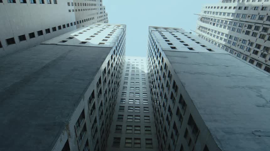 Skyscraper with multiple levels crowds close to other skyscrapers under a clear blue sky