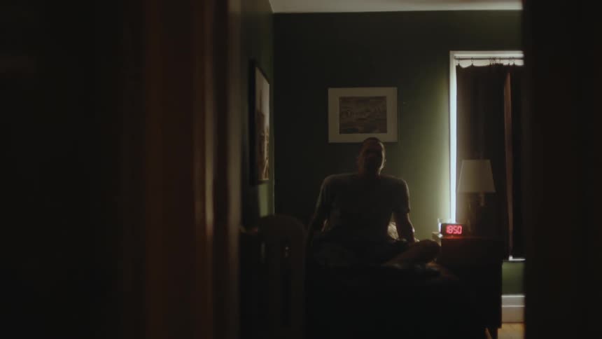 A sleeping man raises an arm to turn off his alarm clock