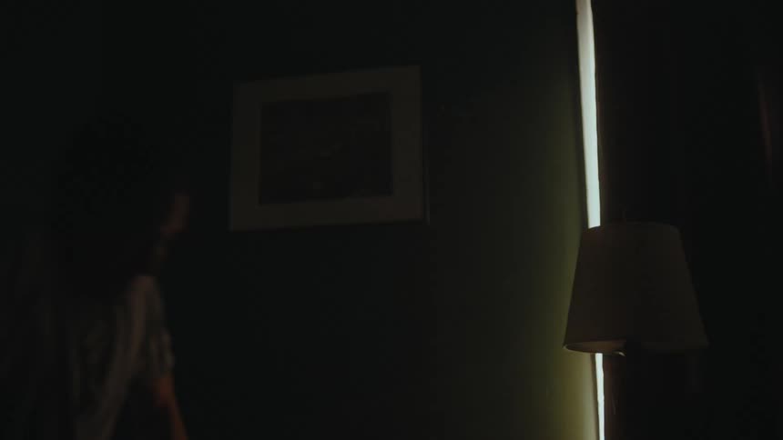 A man wakes up and opens the shades on his window