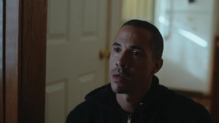 A man is indoors and talking to someone in his house