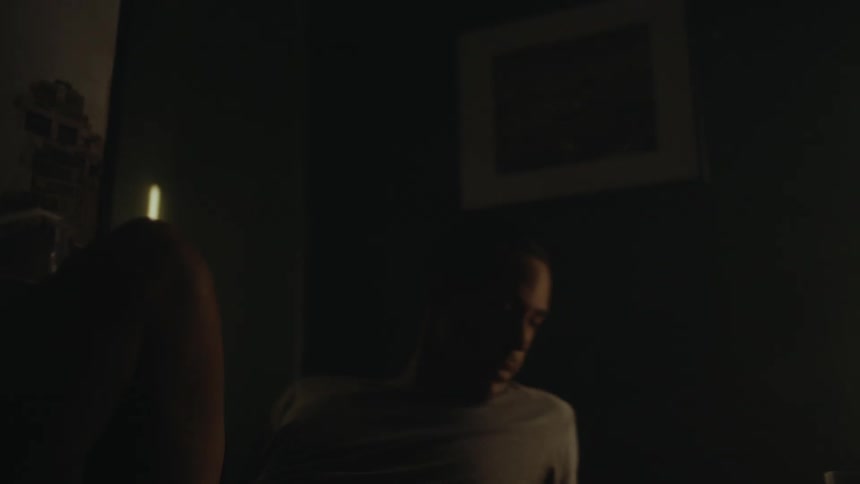 A man lying in bed presses a button on an alarm clock before rising from bed and stretching