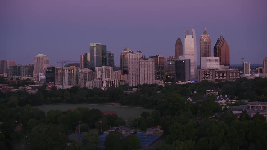 The sun shines on tall city buildings and skyscrapers under a clear sky