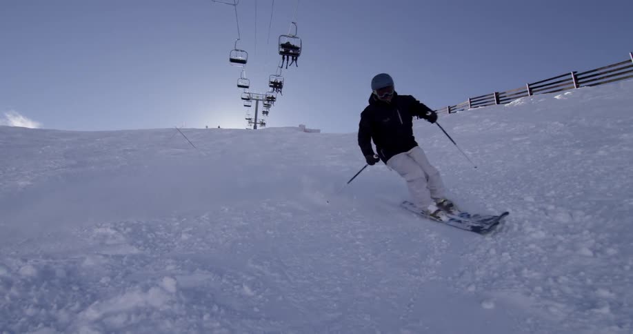 A person travels down a slope skiing fast