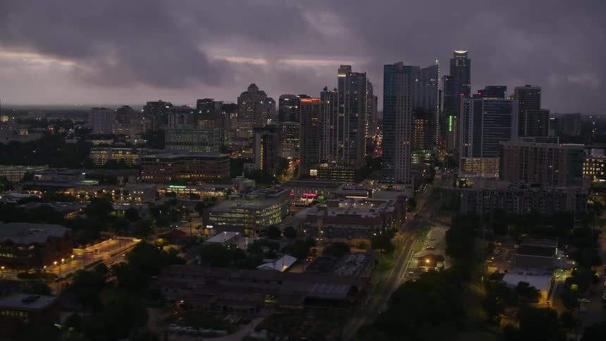 Tall buildings looming over a metropolis on a cloudy evening