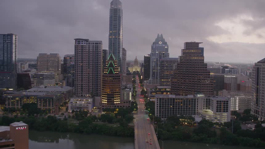 Vehicles drive over a river on a bridge leading in and out of downtown