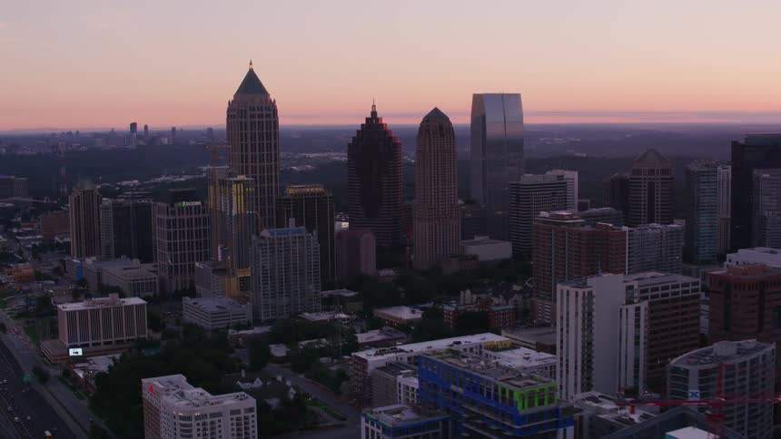 Aerial view of city skyscrapers next to highway at dusk