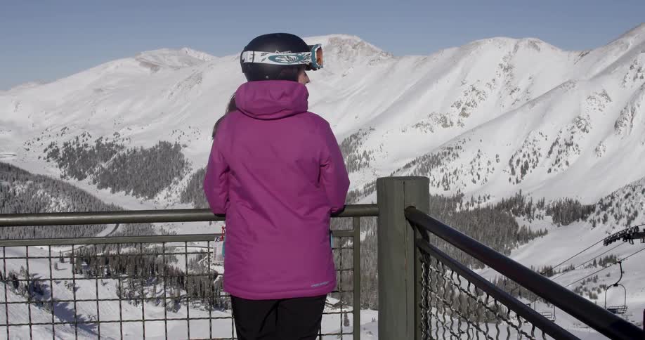 Skier wearing helmet Looks Out Over Snowy Mountains