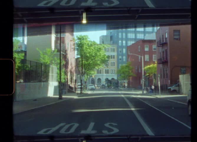 A quiet city street with a person pushing a baby carriage on a sunny day