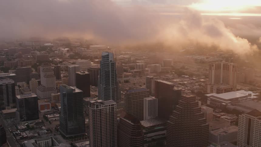 Aerial view of city skyscrapers under the clouds at sunset