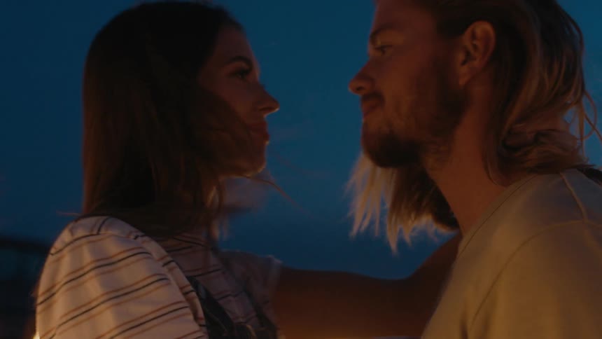A man and a woman are outside dancing and putting their faces close to each other
