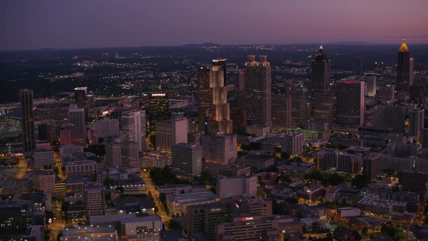 Lights on downtown skyscrapers and buildings glow as the sky grows darker