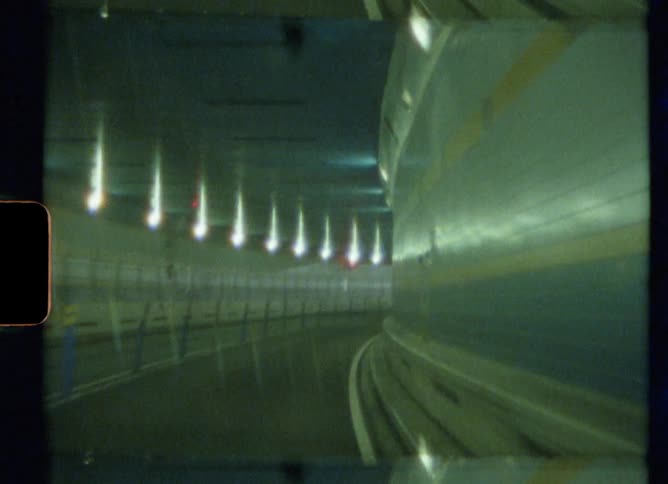 Dashboard view of traveling through a well lit tunnel while in a vehicle