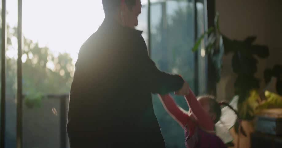 A father and daughter dancing in a room