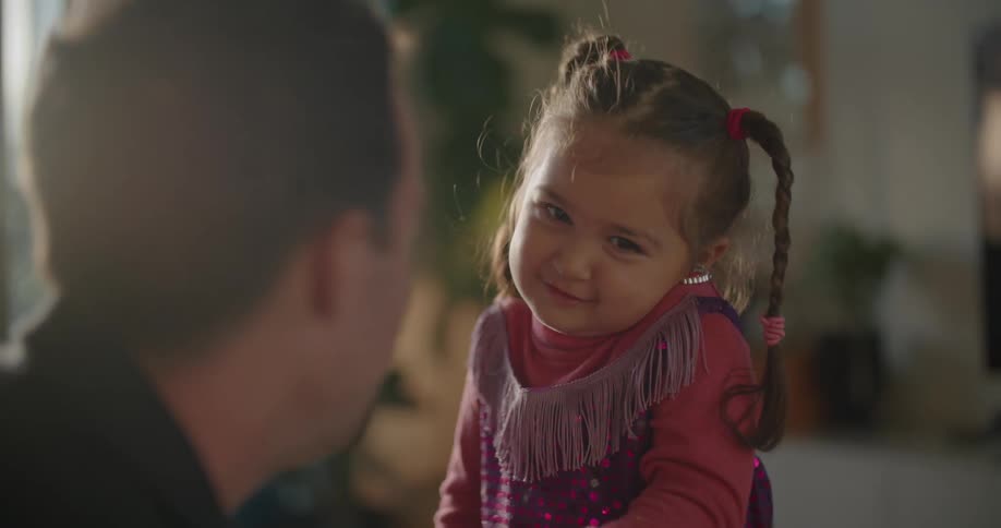 A man attaches a toy earring to the ear of a small girl