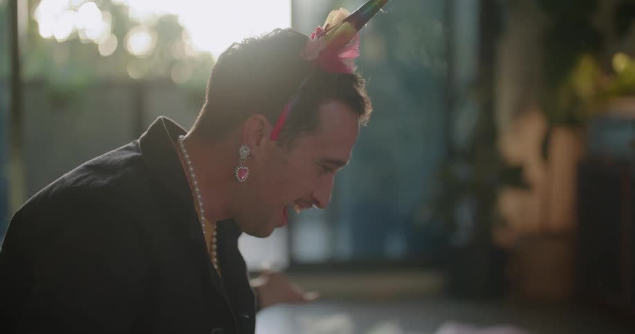 A dad wearing jewelry puts on a hairband playing dress up with his little girl