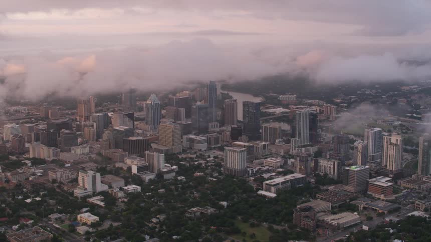 Clouds float over tall buildings and skyscrapers downtown in a big city