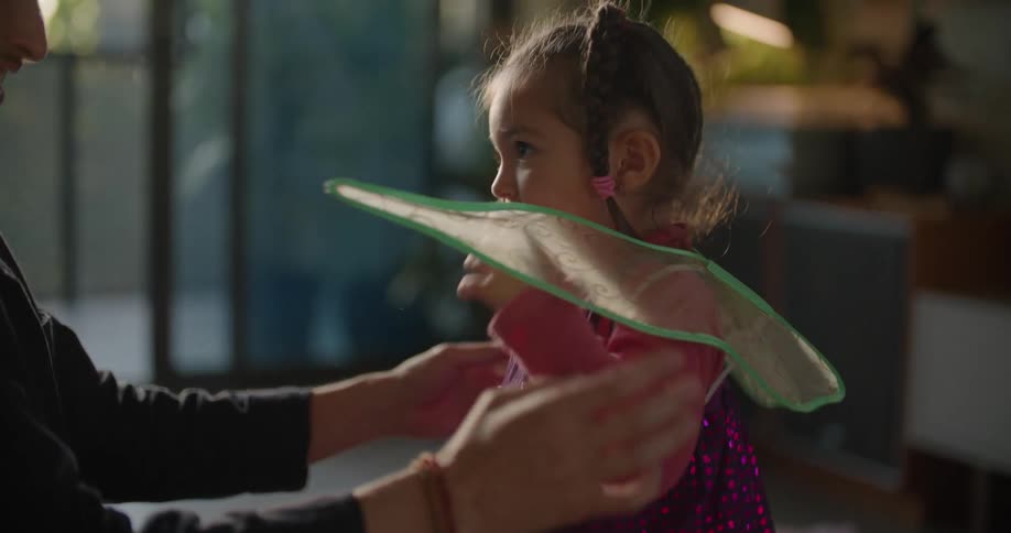 A father putting a costume on his daughter