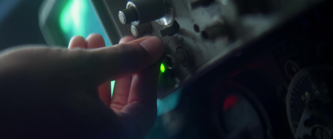 Hand of a man turning a knob on an oscilloscope inside a room