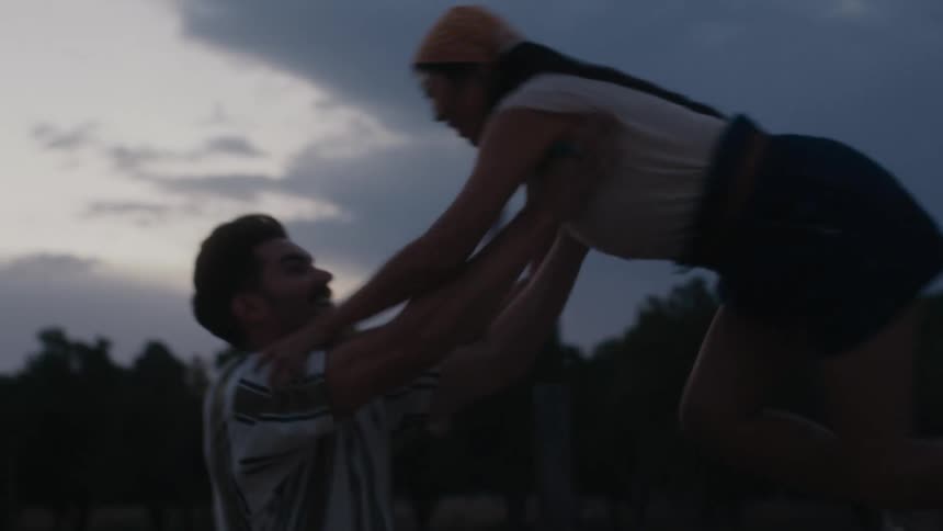 A man helps his girlfriend out of the bed of a pickup truck