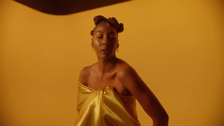A holding a fabric around her body poses while looking into the camera