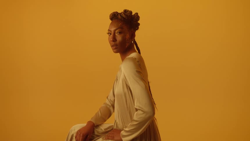 A woman is modeling and sitting on a chair indoors